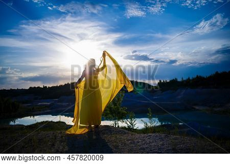 Happy Ukrainian Woman Running In Nature. In A Long Yellow Dress. Symbol Of Freedom Of Ukraine. Woman