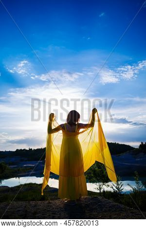 Happy Ukrainian Woman Running In Nature. In A Long Yellow Dress. Symbol Of Freedom Of Ukraine. Woman