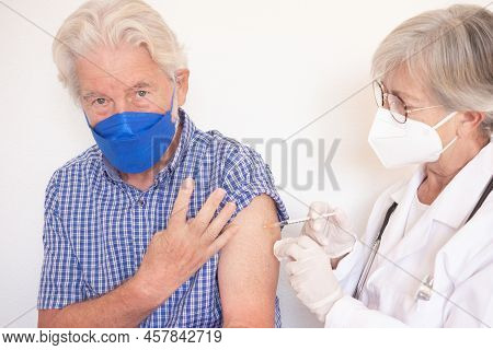 Doctor Giving Injection To Senior Caucasian Man, Old Retired Receiving Fourth Booster Of Covid 19 Va