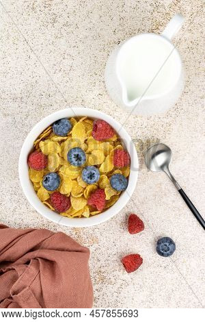 Corn Flakes In A Bowl With Berries, Milk On A Beige Background, Top View. Breakfast With Corn Flakes