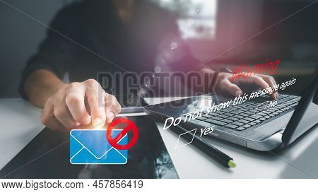 A Businessman Works On A Laptop Computer While A Warning Box Appears On The Screen. Blocking Spam E-