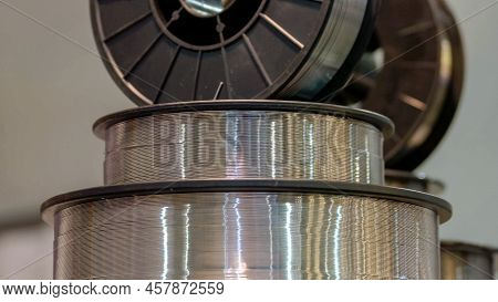 Close-up Pile Of Larhe Industrial Steel Coils. Stack Of Bobbins With Shiny Metallic Wires.