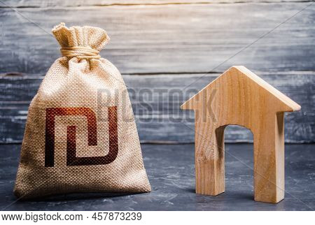 Wooden House And A Israeli Shekel Money Bag. Home Purchase, Investment In Real Estate Construction. 