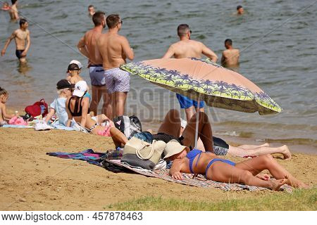 Moscow, Russia - July 2022: People Sunbathing On A Beach On Background Of Moscow River In Strogino. 