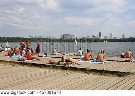 Moscow, Russia - July 2022: People Sunbathing On A Beach On Background Of Moscow River In Strogino. 