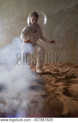 Fear Of The Unknown On Alien Planets. An Astronaut In A White Spacesuit Walks Through An Abandoned C
