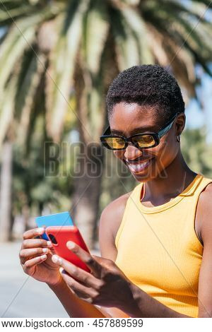 Cheerful African American Woman Online Shopping With Credit Card And Smart Phone In The Street.