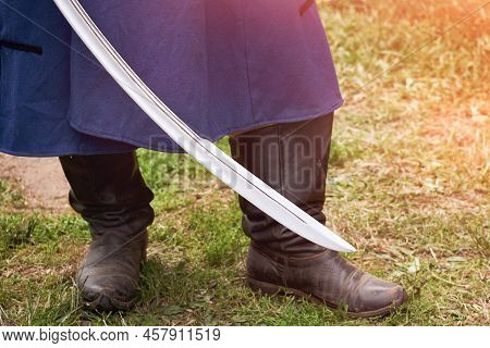 A Man In A Vintage Swedish Military Uniform With A Saber In His Hands. Reconstruction Of The Events 