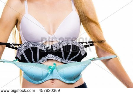 Bosom Concept. Slim Young Woman Wearing Underwear Holding Different Color Bras In Hand, Choosing Whi