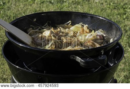 Cooking Outdoors At A Campsite With Fresh Vegetables Meat Cabbage Onion On A Gas Burner With A Woode