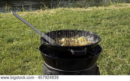 Cooking Outdoors At A Campsite With Fresh Vegetables Meat Cabbage Onion On A Gas Burner With A Woode