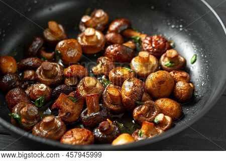 Pan Of Fried Mushrooms Champignons On A Dark Wooden Background. Top View. Place For Text And Copy Sp