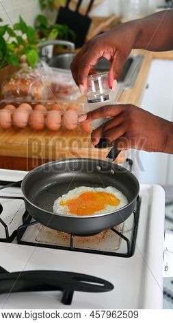 Photo Of Black Hands Which Are Salting A Fried Egg