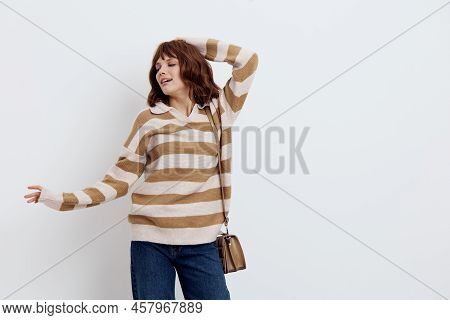 A Pretty Sweet Woman Stands On A Light Background In A Striped Sweater And A Bag On Her Shoulder, Pu