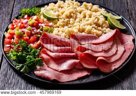 Thinly Sliced Roast Beef Fillet With Quinoa And Tomato Pepper Salsa On Black Plate On Dark Wooden Ta
