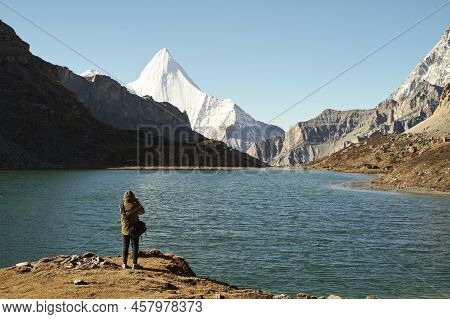 Rear View Of An Asian Photographer Taking A Photo Of The Holy Mount Jampayang And Lake Boyongcuo In 