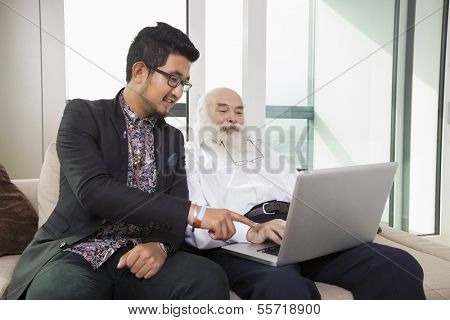 Grandfather and grandson using laptop in living room