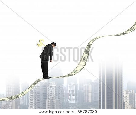 Winder On Businessman's Back Standing On Money Trend With City