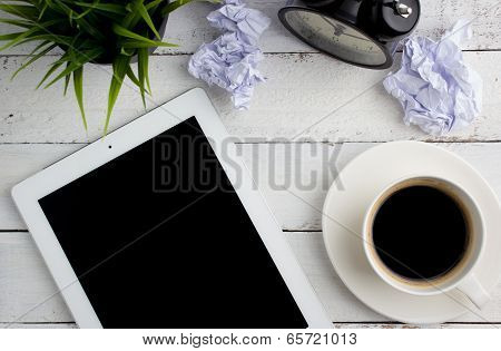 Top view of office desk, a cup of coffee and tablet computer