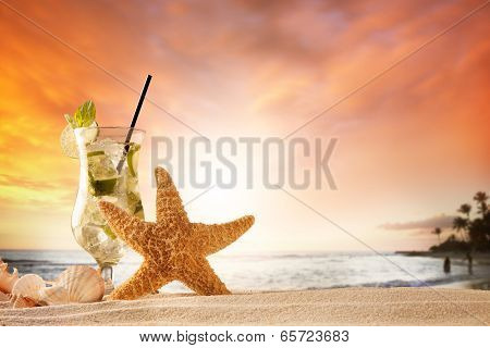 Summer concept with sandy beach, shells and mojito drink