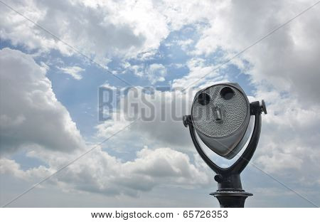 Coin-operated tourist binoculars aimed at a cloudy sky
