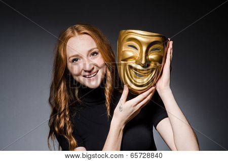 Redhead woman iwith mask in hypocrisy consept against grey background