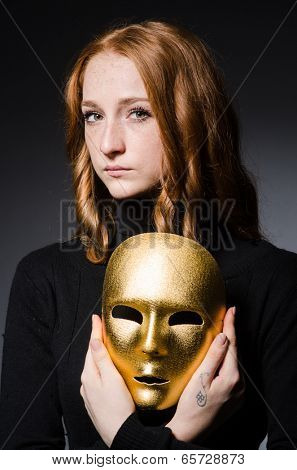 Redhead woman iwith mask in hypocrisy consept against grey background