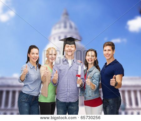 education and people concept - group of standing smiling students with diploma and corner-cap showing thumbs up