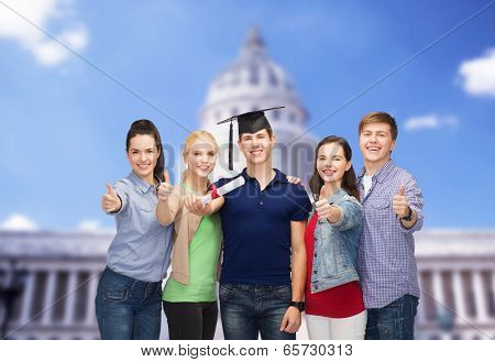 education and people concept - group of standing smiling students with diploma and corner-cap showing thumbs up