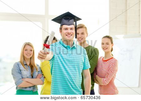 education and people concept - smiling male student with diploma and corner-cap and friends on the back