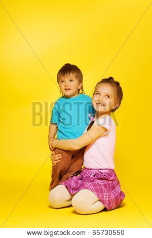 Girl cuddle standing child while sitting on floor