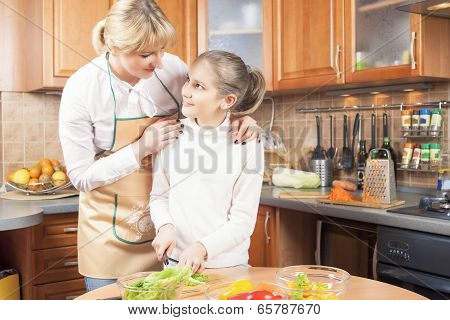 Lovely Mother And Daughter Cutting Vegetables For  Salad Together In The Kitchen