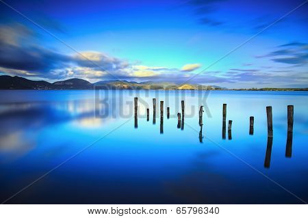 Wooden Pier Or Jetty Remains On A Blue Lake Sunset And Sky Reflection On Water. Versilia Tuscany, It
