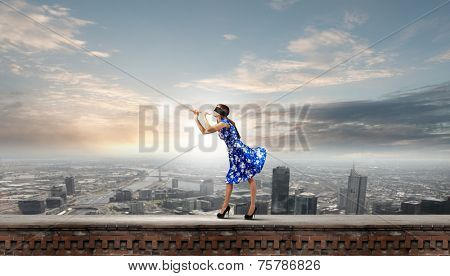 Young woman in blue dress wearing blindfold playing fife