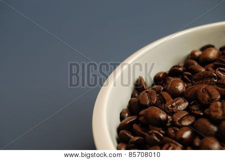 Arabica Coffee Beans in White Bowl Against a Blue Background