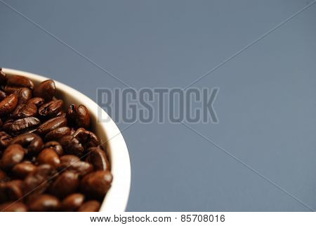 Arabica Coffee Beans in White Bowl Against a Blue Background