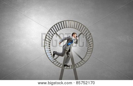 Young businessman running in huge hamster wheel