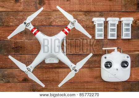 Fort Collins, CO, USA - March 17, 2015:  DJI Phantom 2 with a radio controller and spare LiPo batteries, top view against rustic wooden wood table