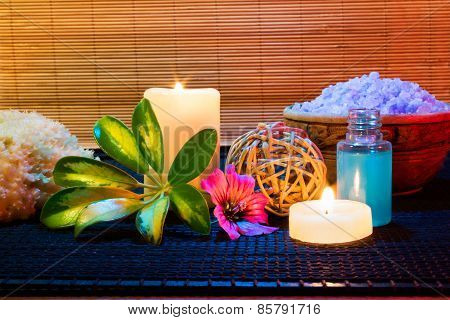 Two candles and and purple hibiscus flower, salt and soap