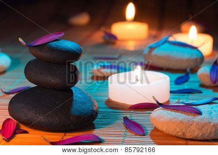 White and black stones, purple petals, and candles