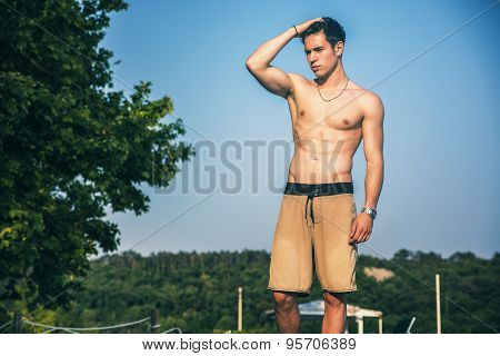 Young shirtless athletic man standing at the beach