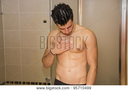 Muscular fit young man applying ointment to his chest