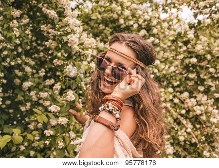 Hippie Young Woman Among Flowers Looking Through Sunglasses