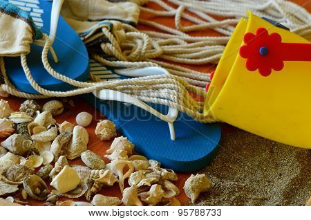 Flip-flops, shells and hammock net on wooden background