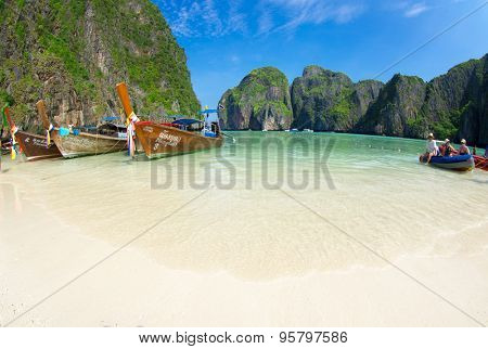    MAYA BAY, THAILAND - FEBRUARY 24, 2012: Visitors wade into the bright blue shallows of Maya Bay, one of the iconic beaches of Southern Thailand.