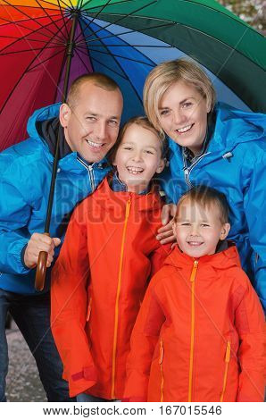 happy and colorful family under umbrella in rainy day