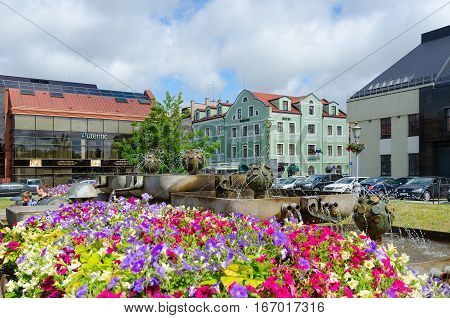 KLAIPEDA LITHUANIA - JULY 11 2015: Unidentified people are relaxing at fountain in front of Salon-shop of amber 