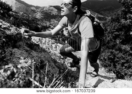 Black-white photo man climbs up rock amidst mountains