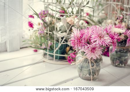 Provence style interior-beautiful pink and purple bouquets in vase and cages over window. Light home decoration with flowers asters. Retro living room. Vintage holiday floral concept. Copy space.