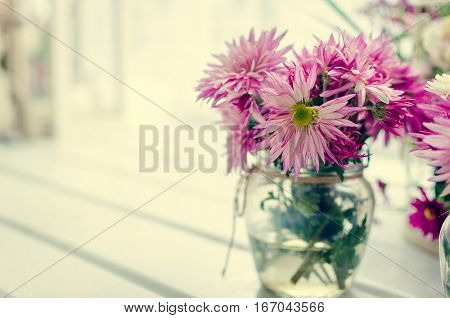 Beautiful pink and purple bouquet in glass vase over window. Light home decoration with flowers asters. Provence style interior retro living room. Vintage holiday floral concept. Copy space.